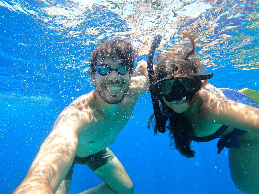 Joana and João snorkelling underwater in bright blue sea.